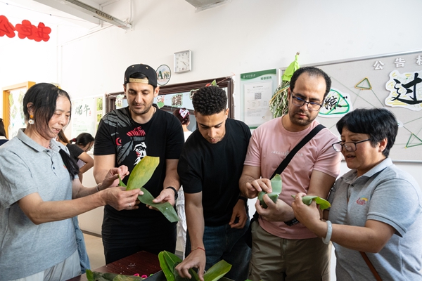 1749455020540722.jpg 图1阿姨教外国同学包粽子.jpg